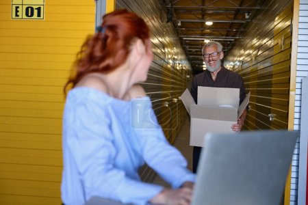 Photo for 35 plus couple communicating in storage warehouse, woman using laptop - Royalty Free Image