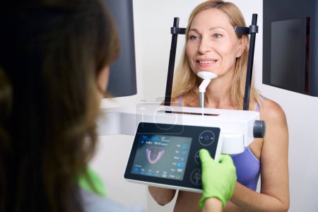 Téléchargez les photos : Patient soumis à une tomodensitométrie par faisceau conique dentaire réalisée par un technologue en radiographie expérimenté - en image libre de droit