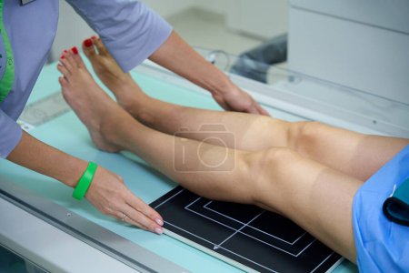 Photo for Cropped photo of radiologic technologist placing patient on x-ray table with legs parallel to surface of image receptor - Royalty Free Image