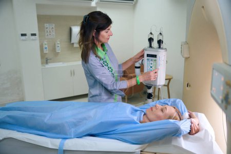 Foto de Radiógrafa experimentada preparando a la paciente para tomografía computarizada con contraste en la clínica - Imagen libre de derechos