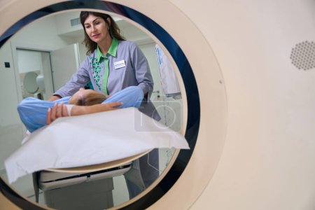 Foto de Cliente de posicionamiento de radiografía femenina en mesa CT con los brazos levantados por encima de la cabeza - Imagen libre de derechos
