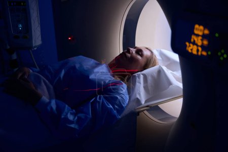 Foto de Paciente acostado en decúbito supino con brazos en el abdomen en la mesa de examen colocada dentro del pórtico de la máquina CT - Imagen libre de derechos