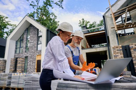 Photo for Builder discussing site development plans with joyous female engineer on building plot - Royalty Free Image
