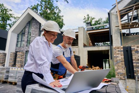 Photo for Cheerful female architect and builder analyzing site development plans on construction plot - Royalty Free Image