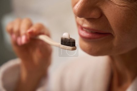 Foto de La señora se cepilla los dientes con un cepillo de dientes y pasta de dientes, la mujer tiene una manicura ordenada - Imagen libre de derechos