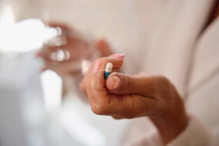 Foto de La mujer tiene una píldora analgésica en la mano, está en el baño - Imagen libre de derechos