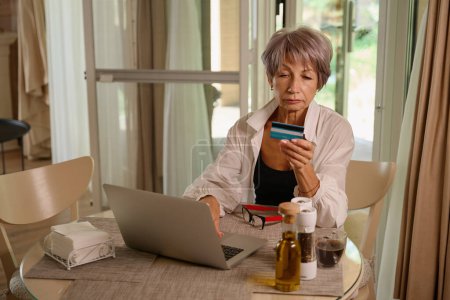 Téléchargez les photos : Belle femme plus âgée faisant des achats en ligne, elle utilise un ordinateur portable - en image libre de droit