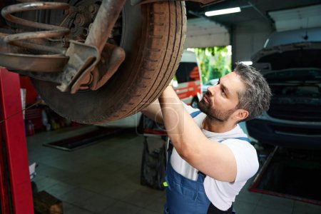 Foto de Técnico de servicio automotriz que realiza inspección de neumáticos en el vehículo de motor cliente en el garaje - Imagen libre de derechos