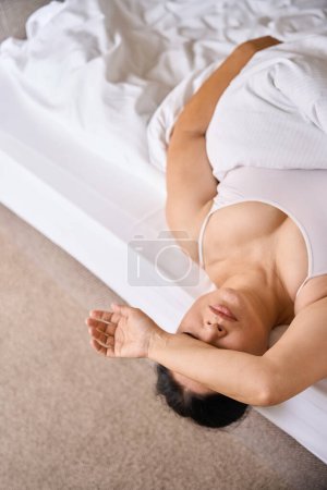 Téléchargez les photos : Femme couvrant ses yeux avec la main tout en faisant une sieste sur un matelas orthopédique au lit - en image libre de droit