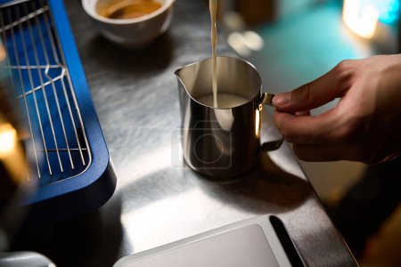 Téléchargez les photos : Barista méconnaissable faisant cappuccino verser du lait pour préparer une tasse de café dans un café - en image libre de droit