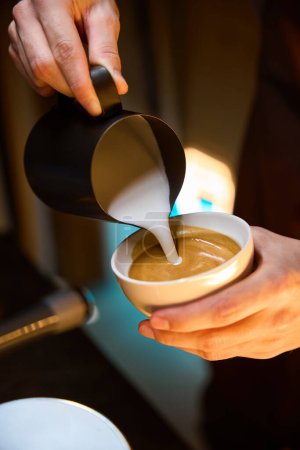 Téléchargez les photos : Main de barista verser de la mousse de lait dans le café expresso dans la tasse de café faire café latte dans le café - en image libre de droit