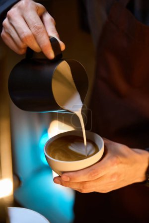 Téléchargez les photos : Barista verser de la mousse de lait dans le café dans une tasse de café caffe latte art servir au client - en image libre de droit