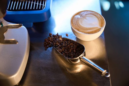 Foto de Granos de café y una taza de deliciosa bebida aromática en cucharada en el mostrador de la cafetería - Imagen libre de derechos