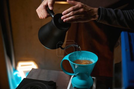 Foto de Barista verter agua sobre granos de café molidos contenidos en el filtro de preparación de café - Imagen libre de derechos