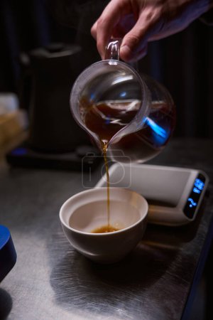 Photo for Unknown bartender pouring hot aromatic from coffee maker into glass cup in coffee house - Royalty Free Image