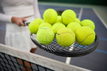 Foto de Jugadora desconocida sosteniendo muchas pelotas de tenis en la raqueta preparándose para el entrenamiento - Imagen libre de derechos