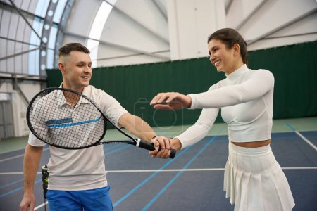 Photo for Confident man teaching woman to properly hold paddle racquet during training on indoor tennis court - Royalty Free Image