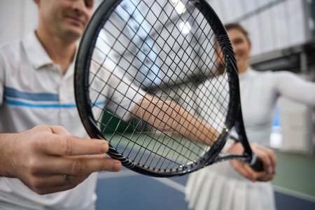 Téléchargez les photos : Gros plan des joueurs de tennis main tenant raquette de tennis se préparant pour le match sur le terrain intérieur - en image libre de droit