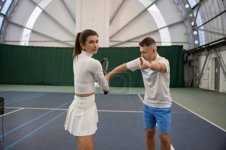 Téléchargez les photos : Instructeur d'homme athlétique avec tennis d'entraînement féminin collaborant sur des techniques efficaces pour améliorer le jeu compétitif - en image libre de droit