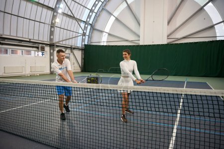 Téléchargez les photos : Joueuse et entraîneur de l'homme pratiquant sur le court de tennis affinant leurs coups et leurs pas avec précision - en image libre de droit
