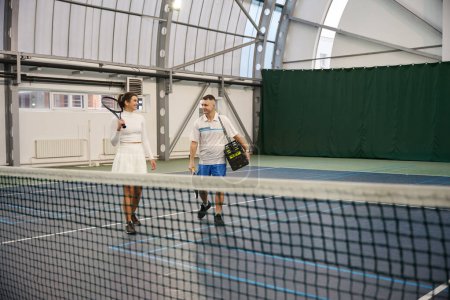 Foto de Alegre hombre y mujer después de jugar al tenis en la cancha cubierta - Imagen libre de derechos