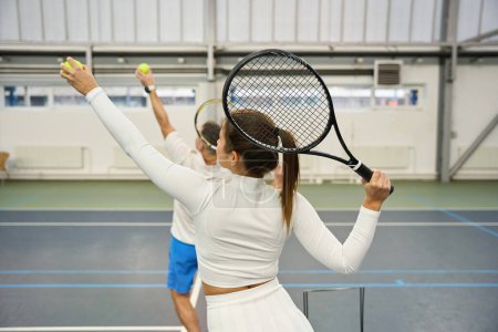 Photo for Sporty man instructor teaching woman to serve tennis ball focusing on technique and concentration - Royalty Free Image