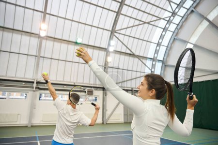Photo for Experienced man coach explaining serving technique to female player during their tennis lesson - Royalty Free Image