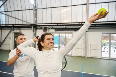Photo for Man trainer guides woman through serving practice in tennis emphasizing sportsmanship and motivation - Royalty Free Image