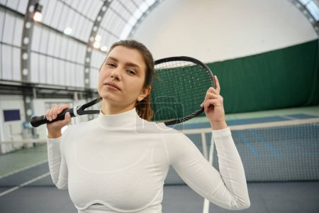 Téléchargez les photos : Femme sportive avec raquette debout en toute confiance sur un court de tennis - en image libre de droit