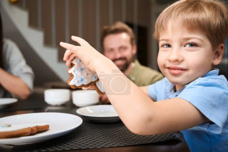 Foto de Delicioso niño disfrutando del desayuno de Navidad en el hotel con su familia durante la celebración de las vacaciones de invierno - Imagen libre de derechos