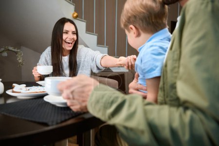 Téléchargez les photos : Femme heureuse prenant le petit déjeuner de vacances avec sa famille à l'hôtel pendant les vacances d'hiver - en image libre de droit