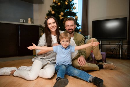 Foto de Familia sonriente posando junto a un árbol de Navidad bellamente decorado celebrando el Año Nuevo con calidez y felicidad - Imagen libre de derechos
