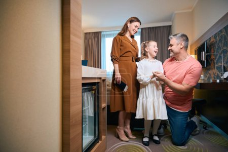 Photo for Happy caucasian family of mother, father and daughter in hotel room. Concept of rest, vacation and travelling. Idea of family relationship and spending time together - Royalty Free Image