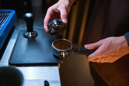 Photo for Unrecognizable barista holding portafilter and coffee tamper making espresso coffee in cafe - Royalty Free Image