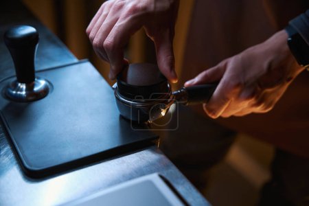 Téléchargez les photos : Cafetière nivellement café moulu dans portafilter avant extraction dans le café-restaurant - en image libre de droit