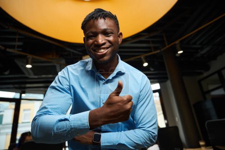 Photo for Happy African American man showing thumbs up and laughing looking at camera, employee of company satisfied with his well-paid job and great opportunities - Royalty Free Image