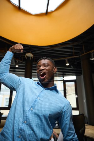 Photo for Funny self-confident man showing his arm muscles making yes gesture, extremely happy african american man posing at camera, high-qualified employee of analytics company - Royalty Free Image