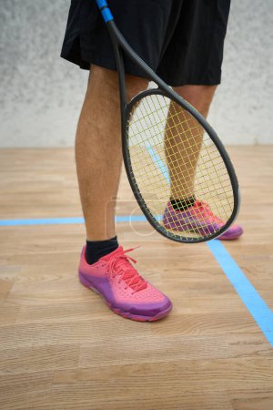 Téléchargez les photos : Homme en pantalon de survêtement noir et baskets tenant la raquette squash espace de copie - en image libre de droit