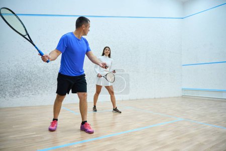 Photo for Man instructor fervently teaching woman to play squash exercising on indoor court - Royalty Free Image