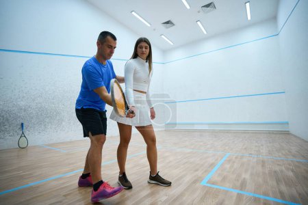 Téléchargez les photos : Joueuse de squash et entraîneur de l'homme participent activement mettant en évidence les compétences de frappe raffinées sur le terrain intérieur - en image libre de droit