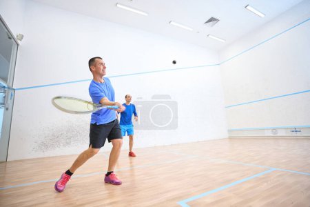 Téléchargez les photos : Des hommes actifs s'entraînent dans des matchs amicaux de squash sur un terrain intérieur - en image libre de droit