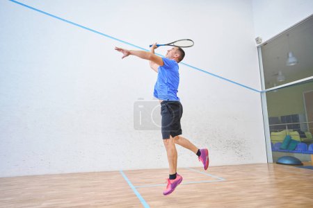 Foto de Slim hombre deportivo jugando squash solo en la cancha cubierta - Imagen libre de derechos