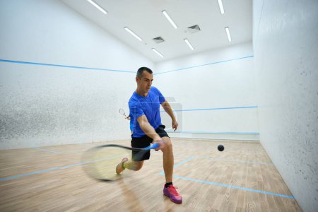 Téléchargez les photos : Jeune homme joueur de squash jeu d'exercice dans la salle de gym - en image libre de droit