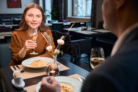 Téléchargez les photos : Femme caucasienne heureuse adulte et homme cultivé griller du vin à partir de verres dans le restaurant de l'hôtel. Concept de date et d'événement romantique - en image libre de droit