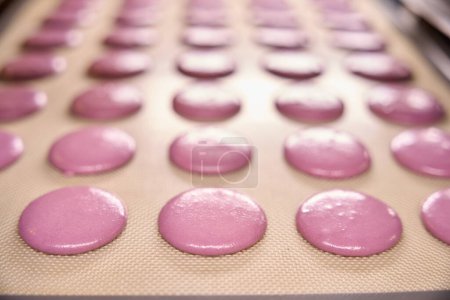 Foto de Primer plano de las conchas de macarón rosa brillante en la estera de silicona en la bandeja para hornear - Imagen libre de derechos