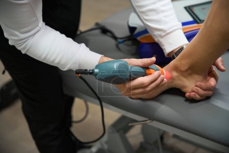 Téléchargez les photos : Photo rapprochée de la femme faisant l'objet d'une thérapie laser pour réduire l'enflure et l'inflammation à pied - en image libre de droit