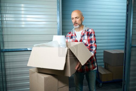 Photo for Old guy holding a cardboard box with things while moving - Royalty Free Image