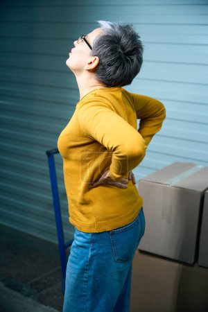 Photo for Adult woman strained her back while transporting things in cardboard boxes. - Royalty Free Image