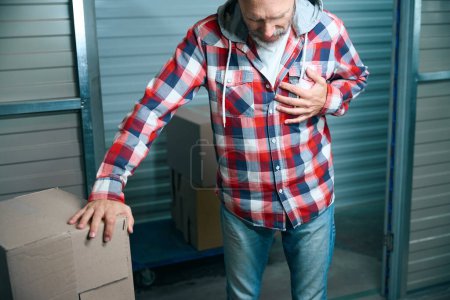 Foto de Hombre calvo siente dolor en el corazón después de transportar las cosas al almacén de almacenamiento - Imagen libre de derechos