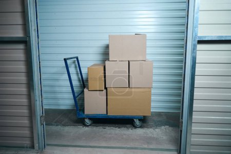 Photo for Things folded in cardboard boxes stand in a stack on a blue cart - Royalty Free Image